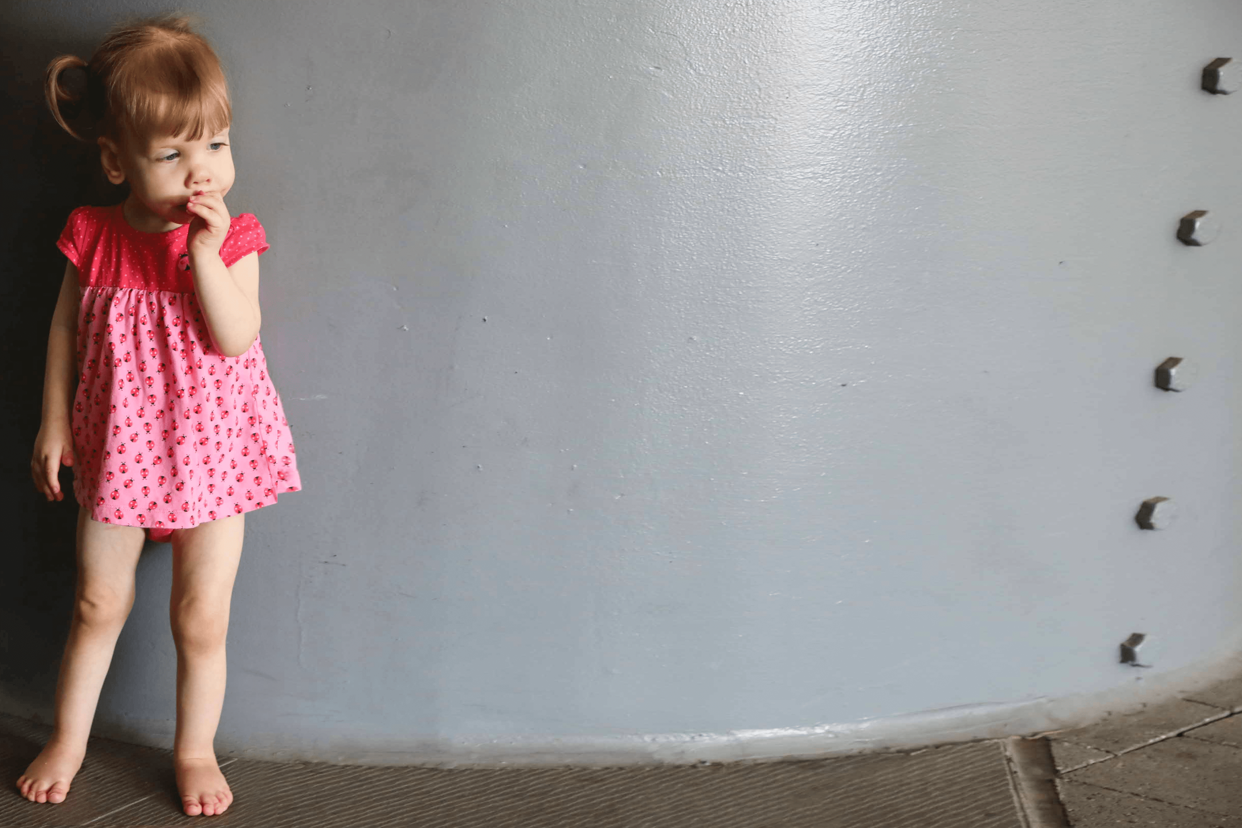 Little girl standing by pillar